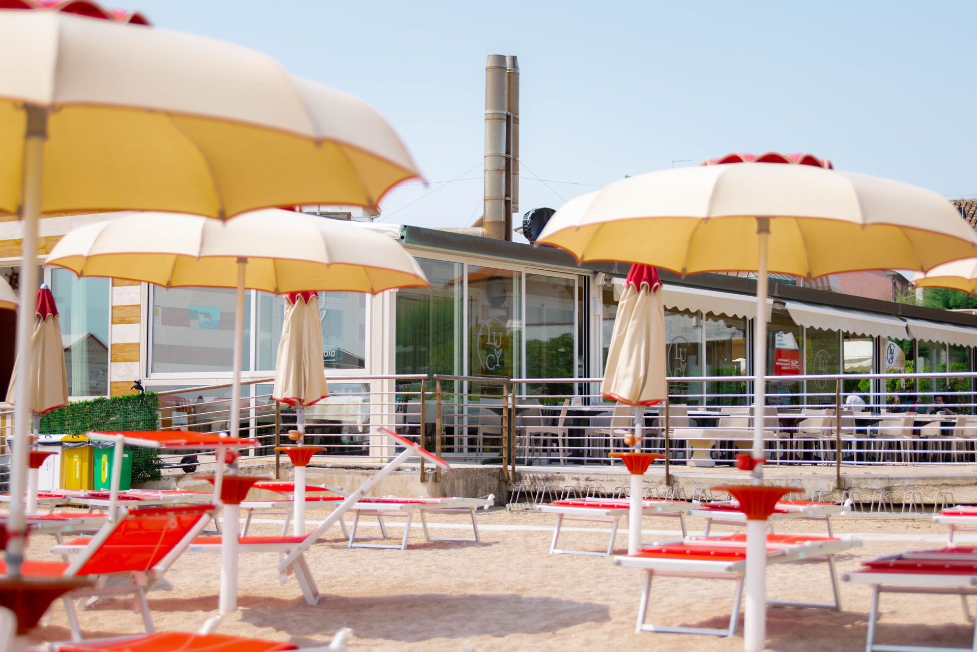 Terrazza sulla spiaggia con ombrelloni e lettini davanti al ristorante