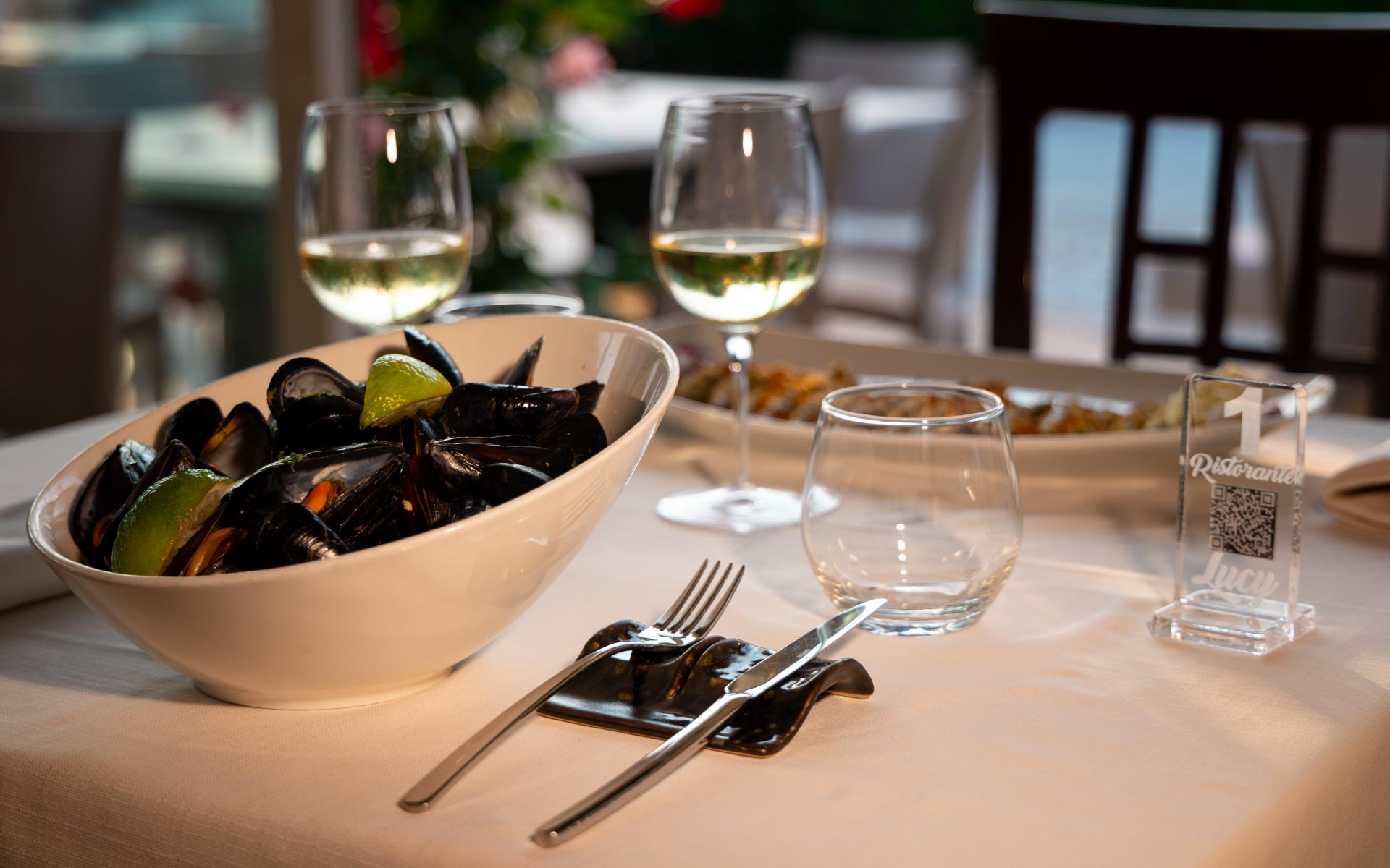 Cozze in una ciotola bianca con limone e calici di vino bianco