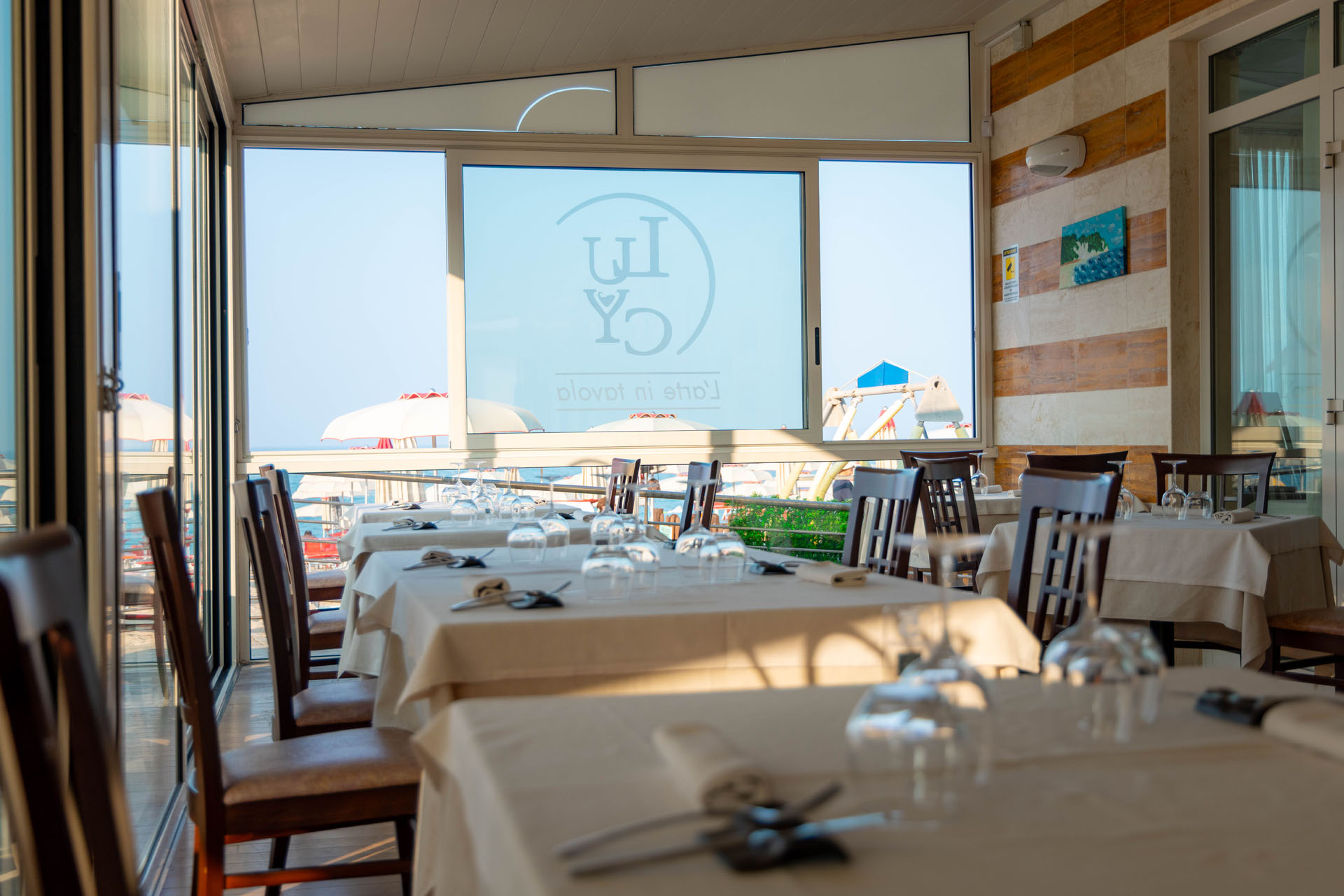 Sala con grande vetrata affacciata sul mare e logo Lucy