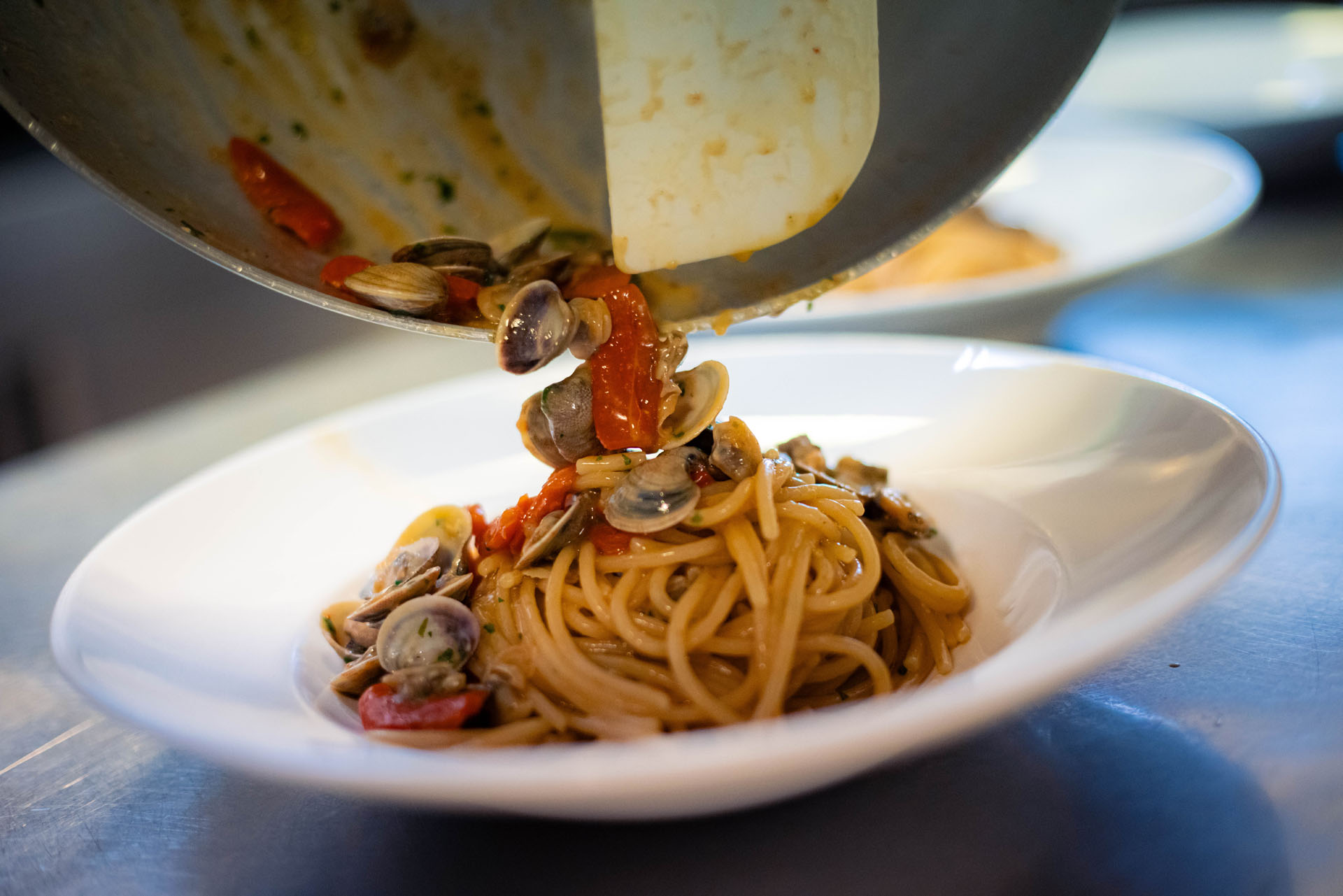 Pasta con vongole versata dalla padella al piatto
